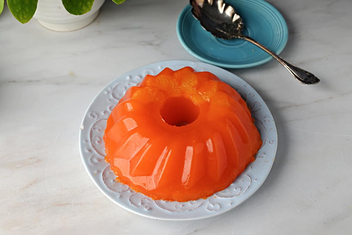 an orange sherbet salad made in a mold and now on a plate ready to serve.