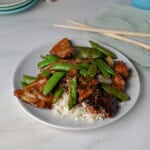 a plate of pork stir fry with sugar snap peas.