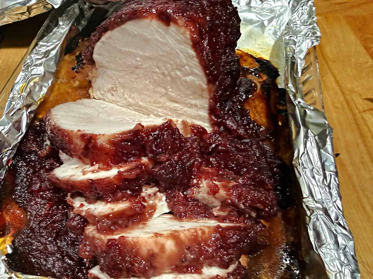 cranberry glazed turkey breast sliced in the pan.