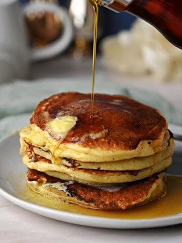 a stack of Greek yogurt pancakes with melting butter and drizzling syrup, ready to eat.