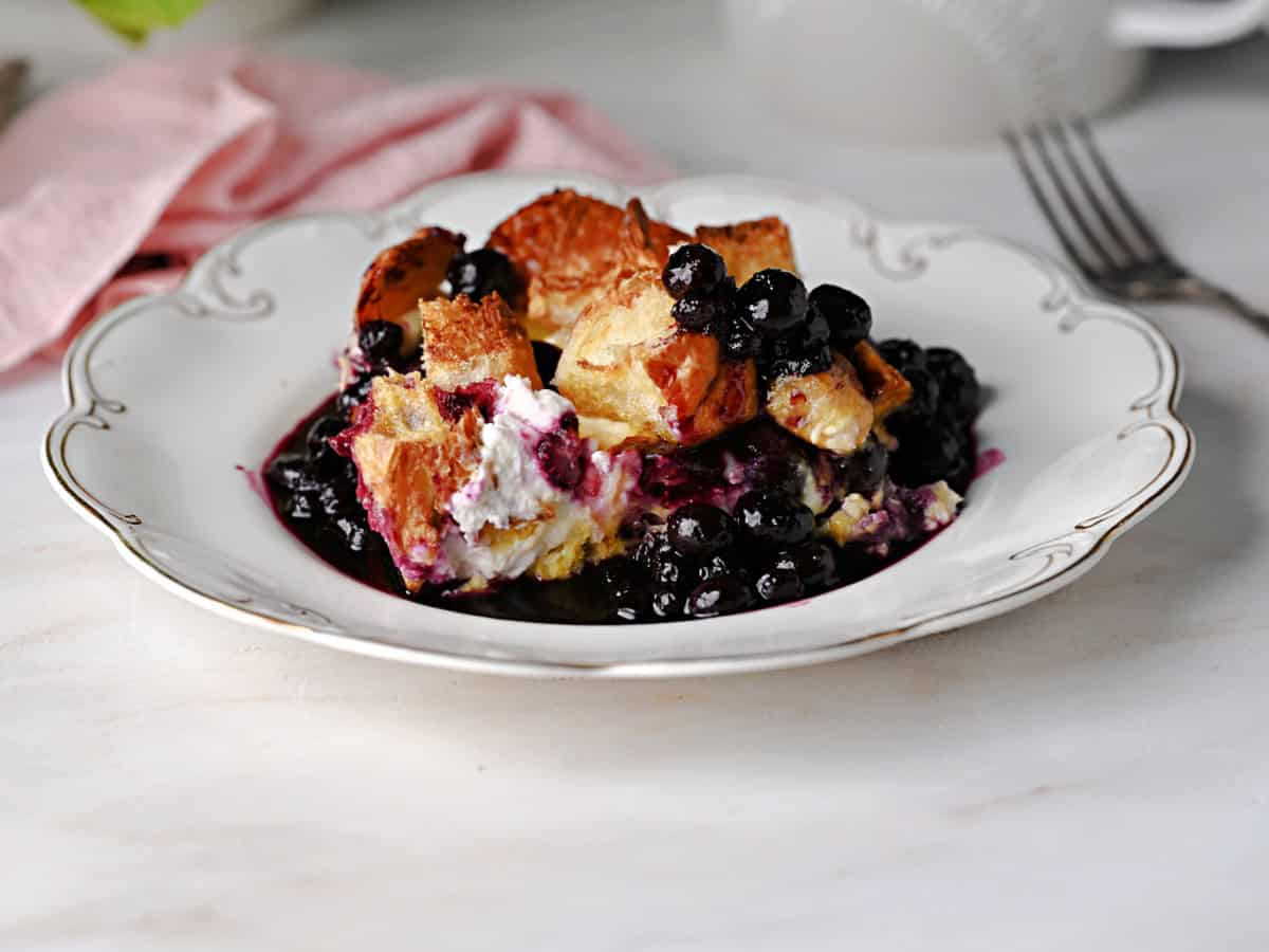 a serving of overnight french toast bake with blueberry sauce.
